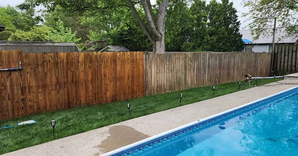 Wood fence half restored by washing, showing the clean-vs-weathered difference